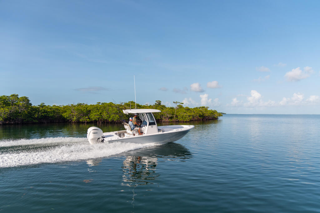 White center console boat running through shallow mangrove waters in clear blue conditions