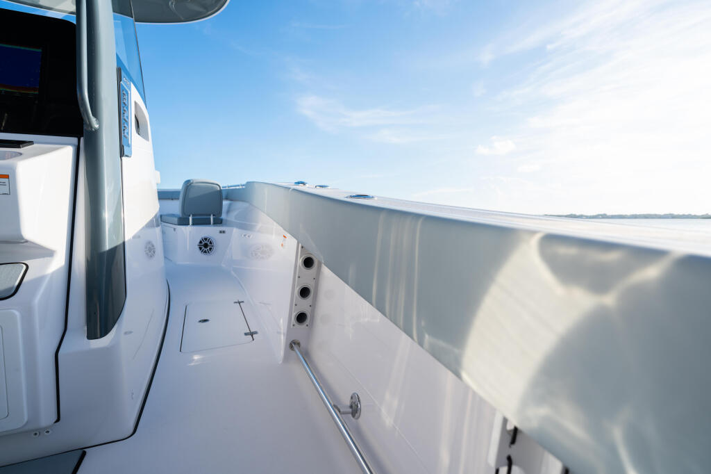 Starboard side deck of white boat with railing and calm water visible beyond hull