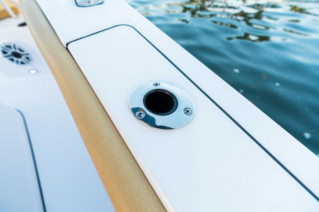 Chrome-trimmed flush-mount rod holder installed on boat gunwale with water and seaweed visible nearby