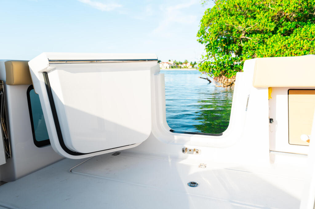 Boat cabin interior with open window showing calm water and mangrove shoreline