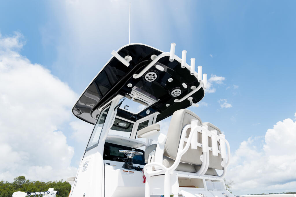 White fiberglass center console boat with hard-top canopy and integrated lighting against blue sky