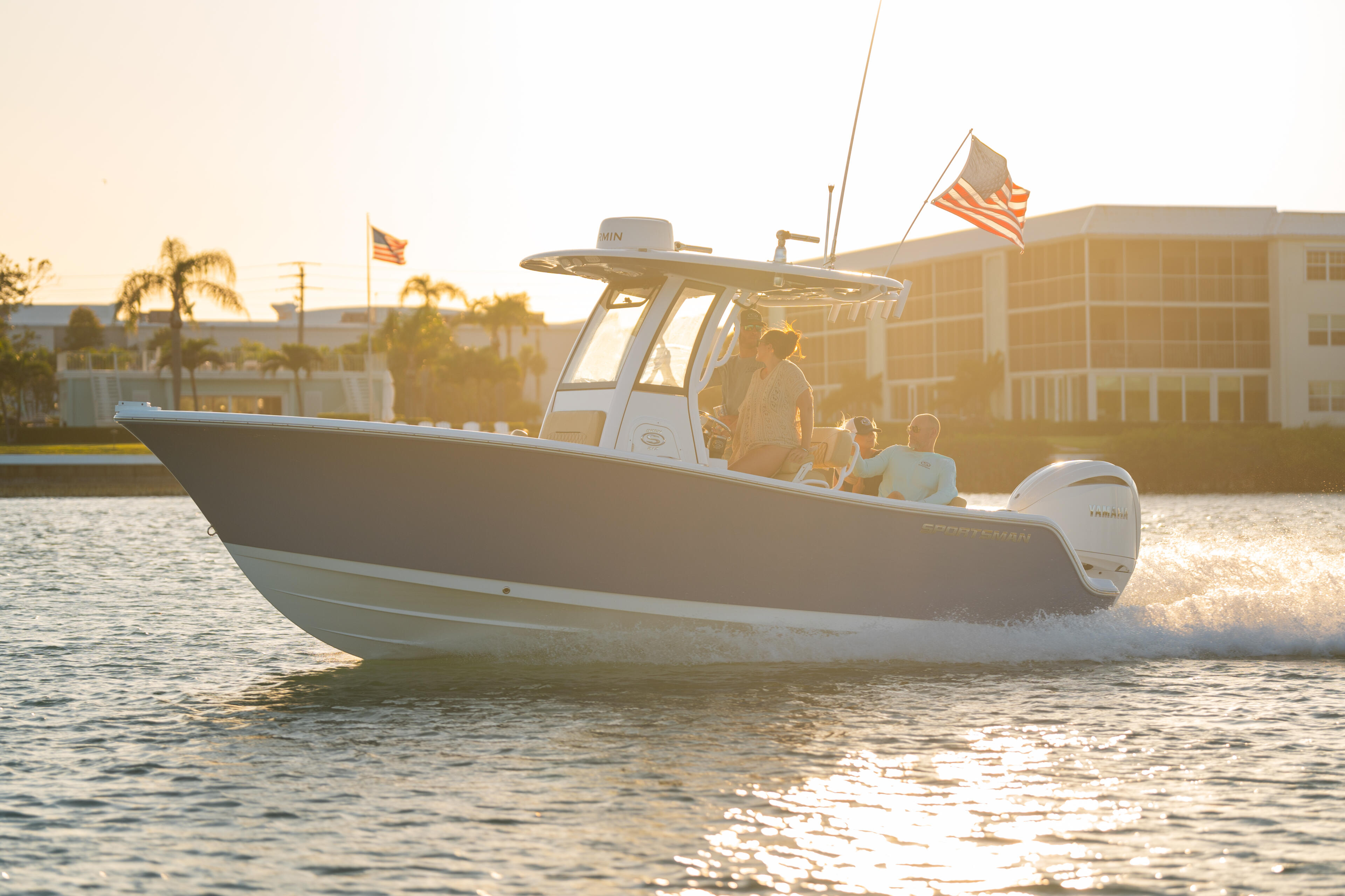 Couple enjoying a boat cruising near a sandbar at sunset with coastal buildings in the background