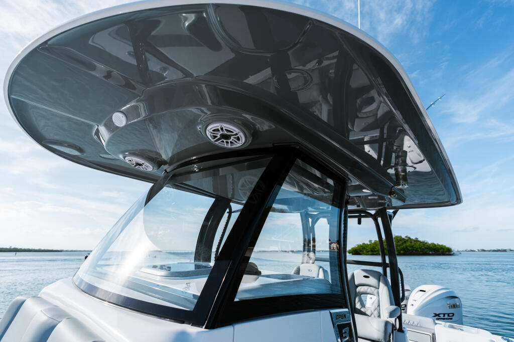 Hard-top helm station with tinted windshield and gauges on a center console boat at anchor in shallow blue water