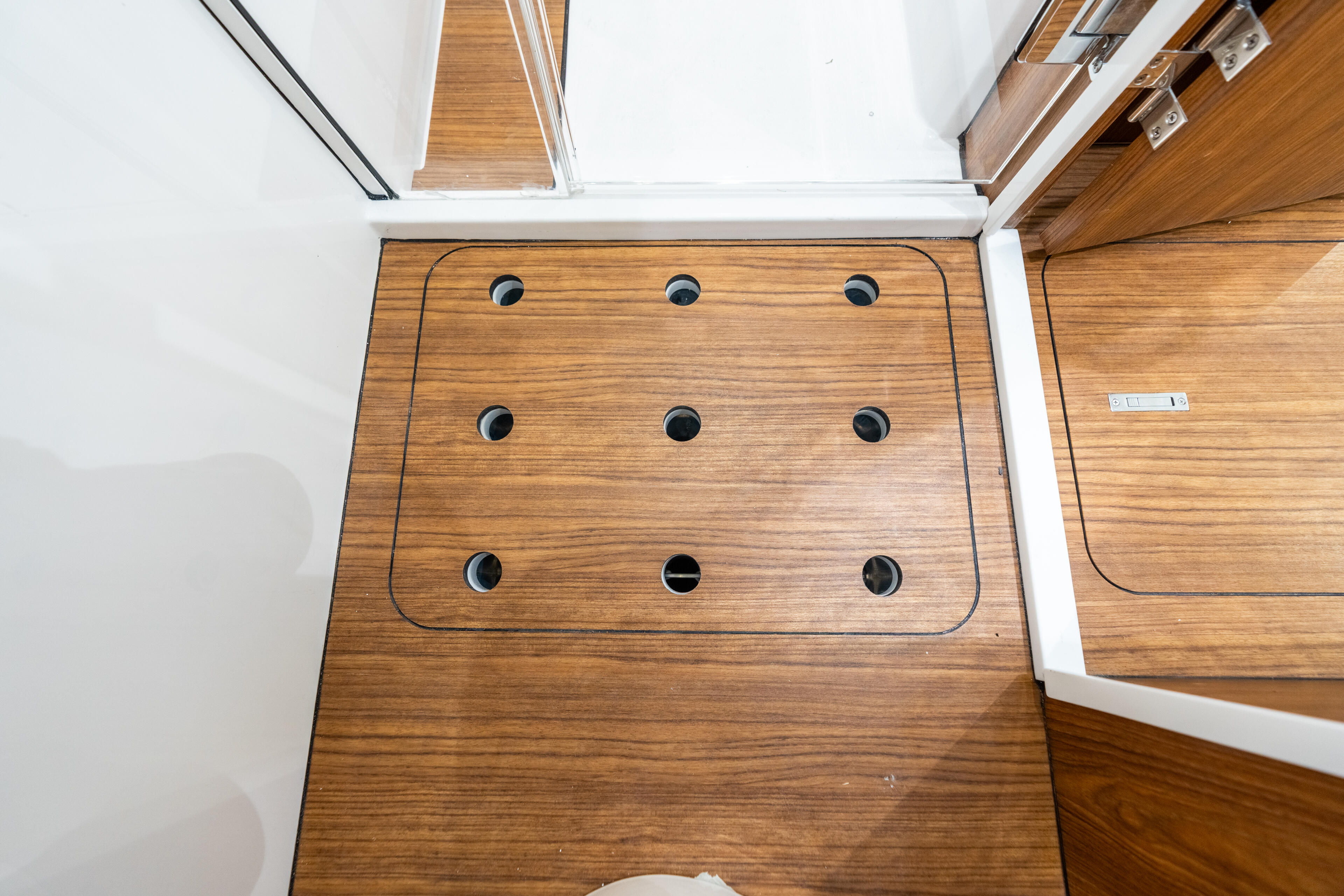 Cabin floor with nine in-floor vertical rod holders arranged in a grid pattern on teak wood decking