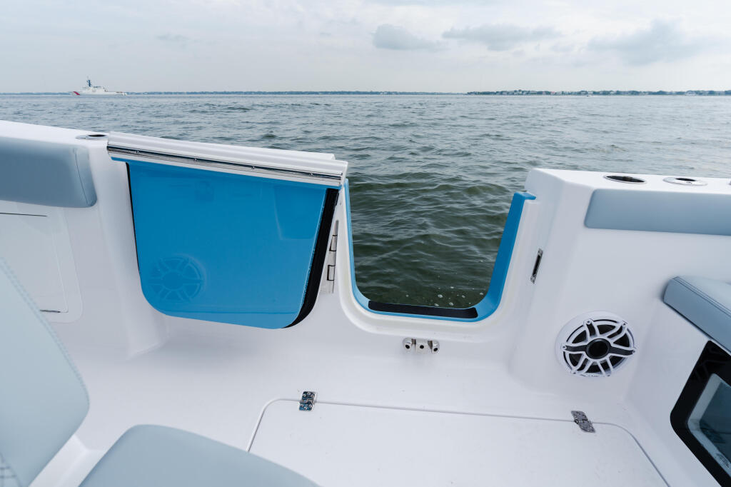 Boat cabin exterior with blue-trimmed windows, white hull, and speaker detail overlooking open water