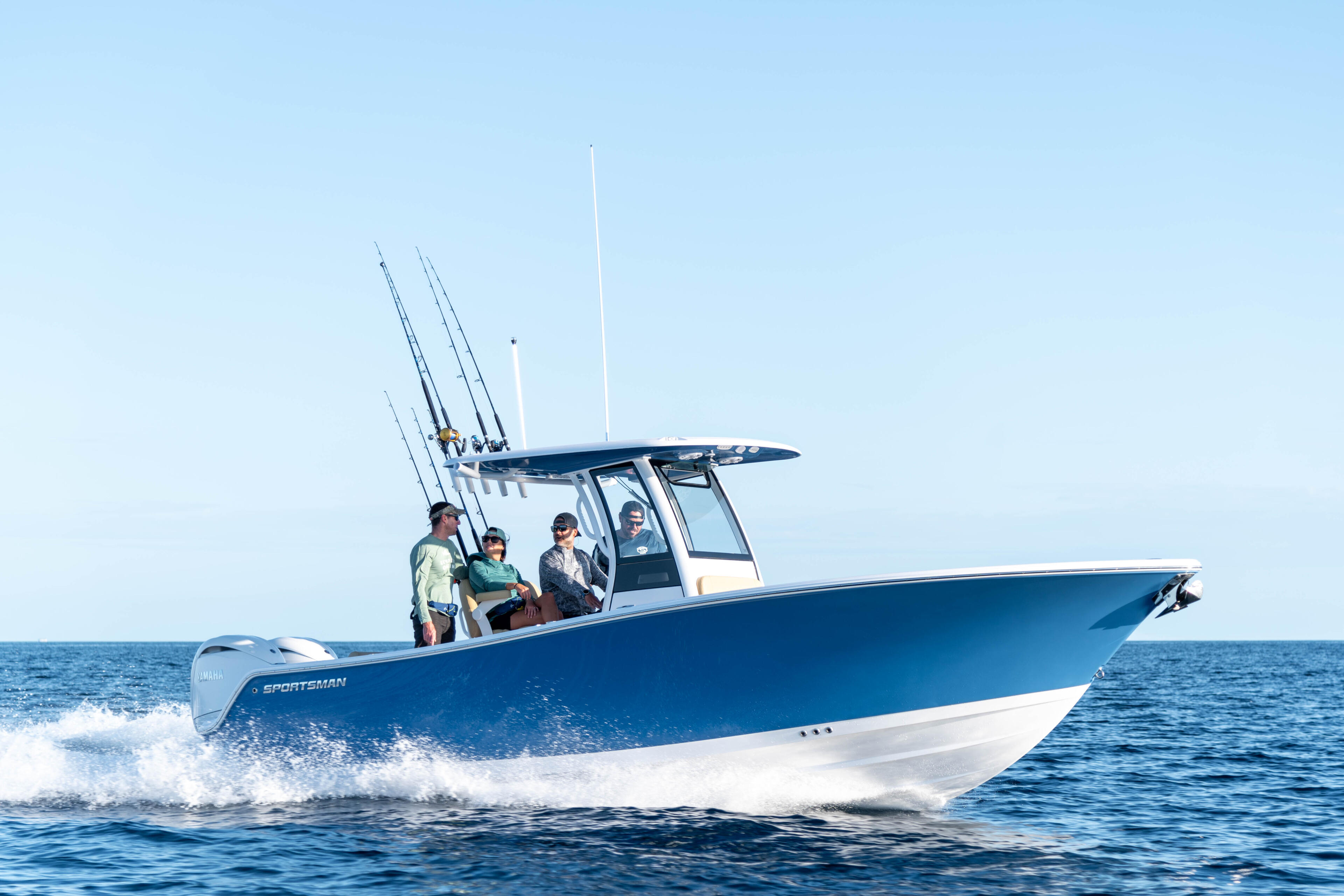 Blue and white sportsman fishing boat with four people running through ocean waves