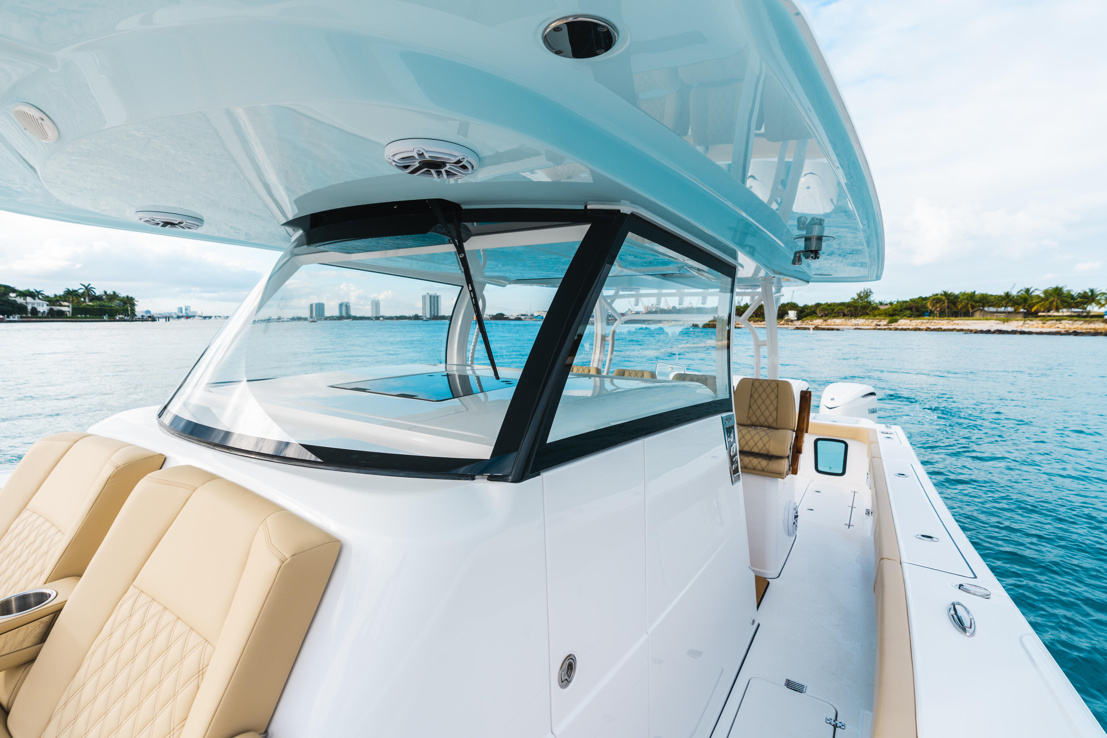 Modern center console boat with hard-top canopy and panoramic windshield on calm turquoise water