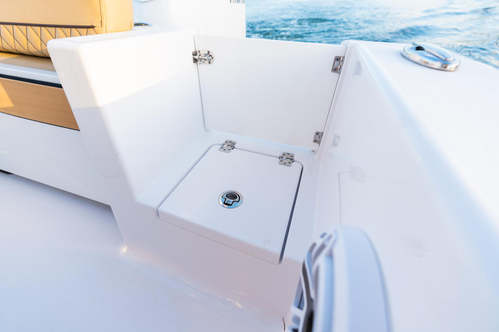 Open transom door and storage compartment on boat's starboard side with ocean water visible in background