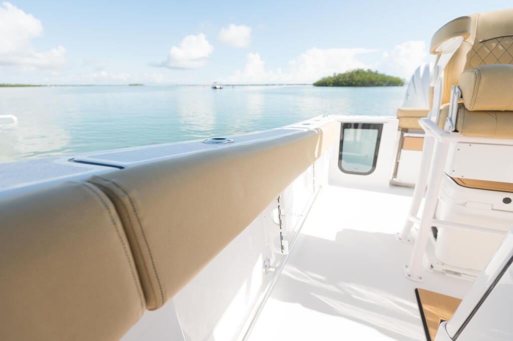 Tan padded helm seating and white console with windshield overlooking calm turquoise water and mangroves