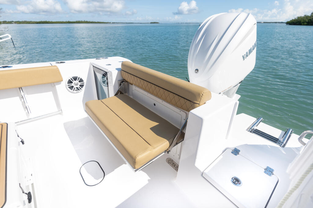 Center console boat with tan convertible rear seating and Yamaha outboard motor anchored in turquoise water