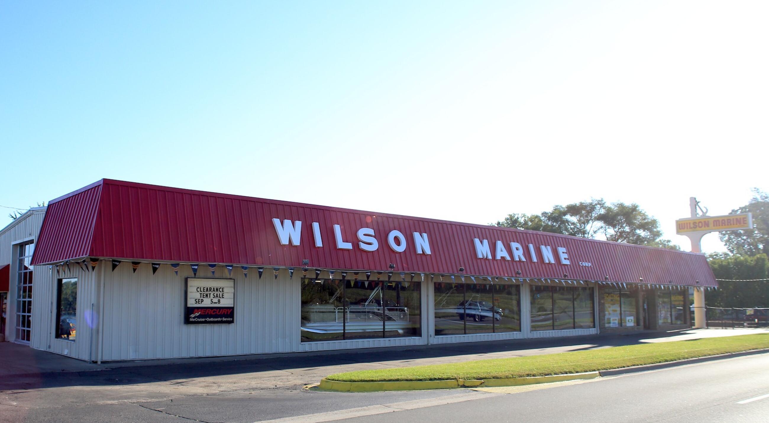 Wilson Marine dealership storefront with red metal roof and large display windows showing boats inside