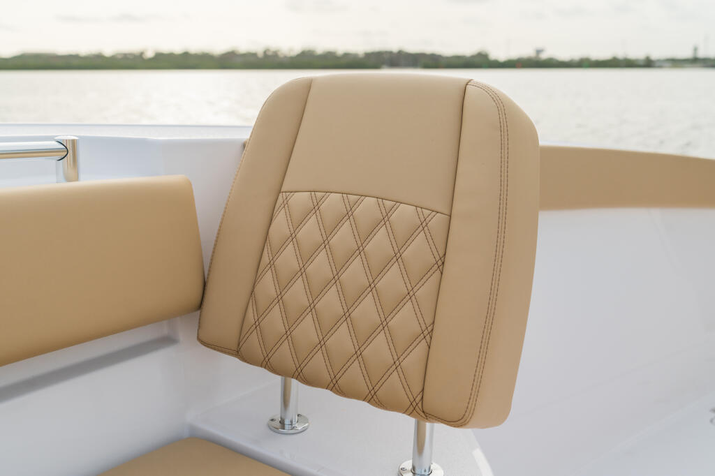 Tan upholstered boat seat with quilted diamond pattern detail and chrome pedestal base on water