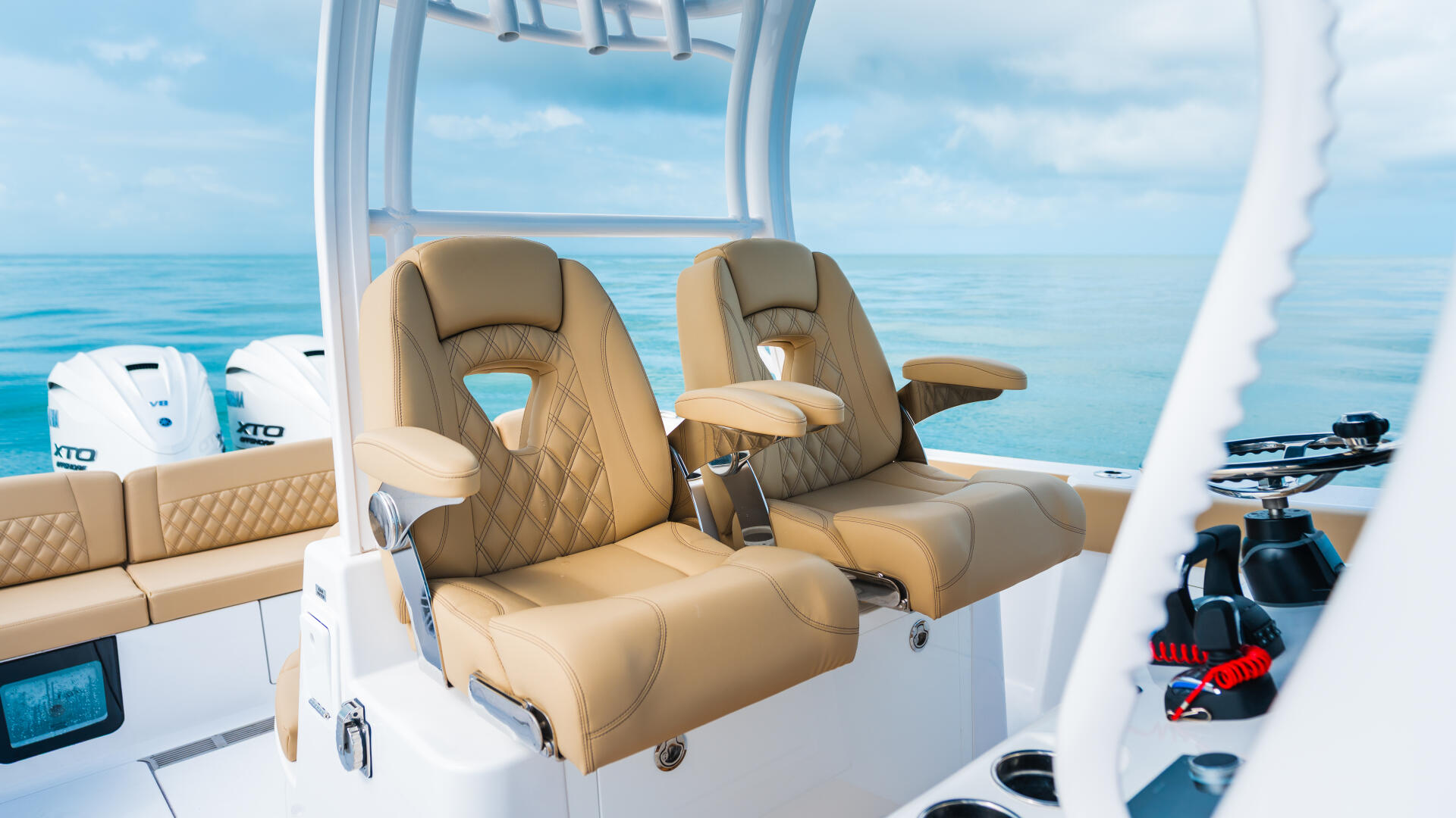 Tan leather captain's seats with armrests on a white center console boat overlooking calm blue ocean