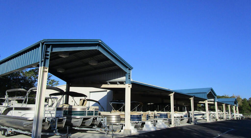 Boat dealership with covered boat slips and pontoon boats under metal-frame canopy structures