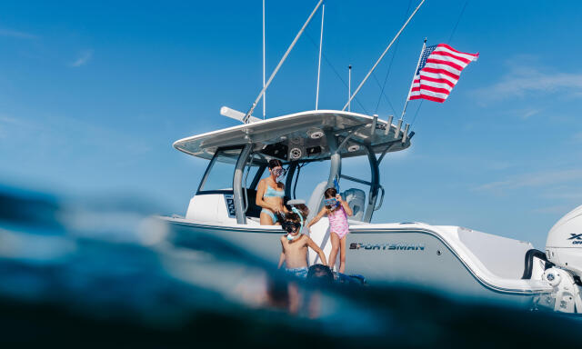 Family enjoying time together on a Sportsman boat in clear blue water with American flag flying