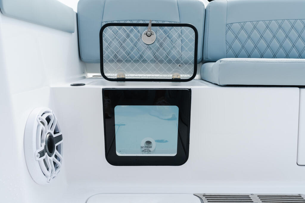 Cabin window and audio speaker detail on boat exterior with light blue upholstered seating visible above