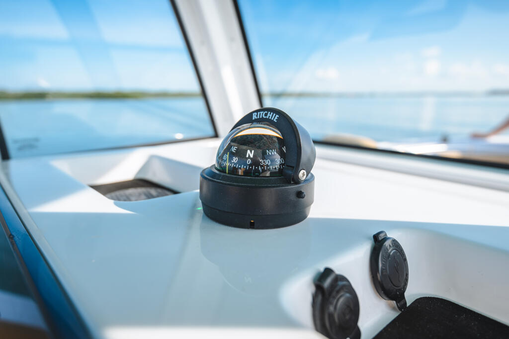 Ritchie compass mounted on the helm console of a center console boat with calm water in the background