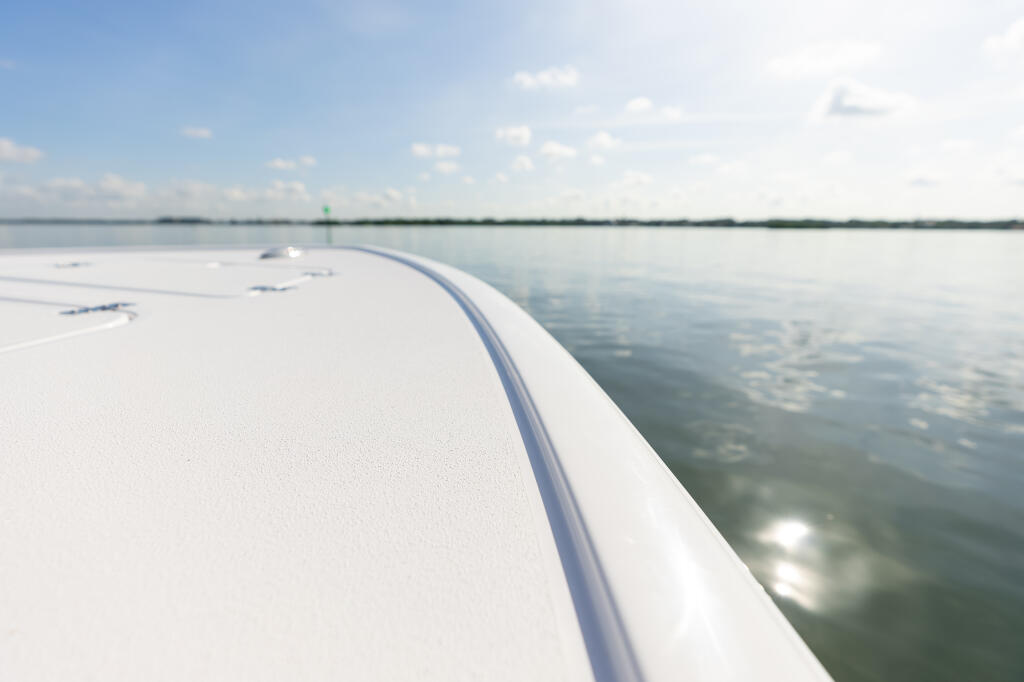 Boat's white bow rail and gunwale with calm water and distant shoreline