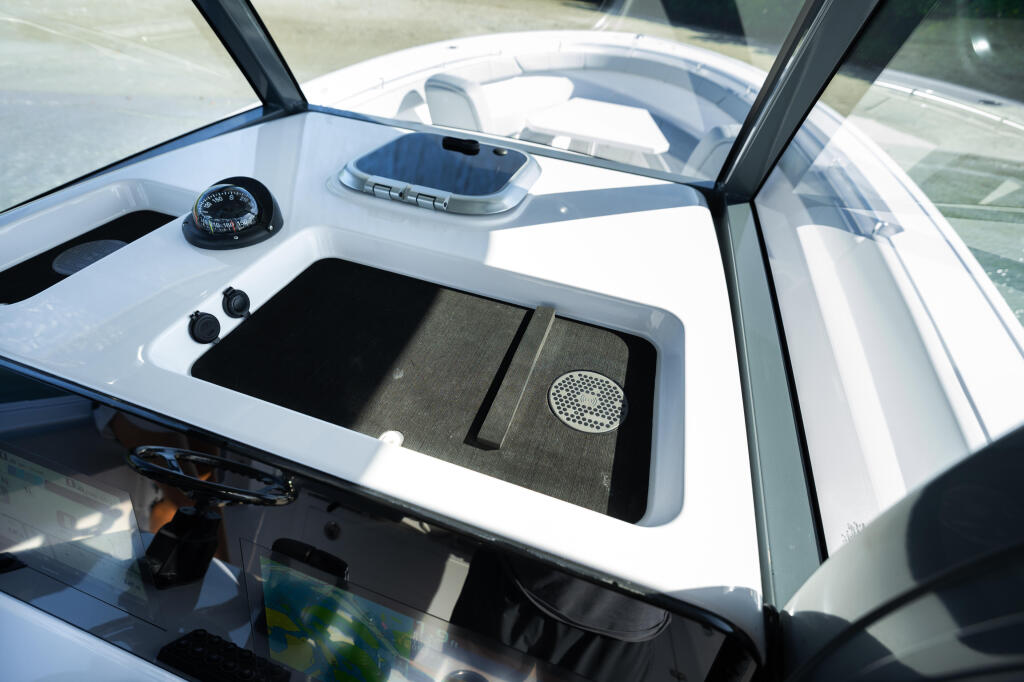 Helm station with compass, controls, and storage compartment visible through open windshield