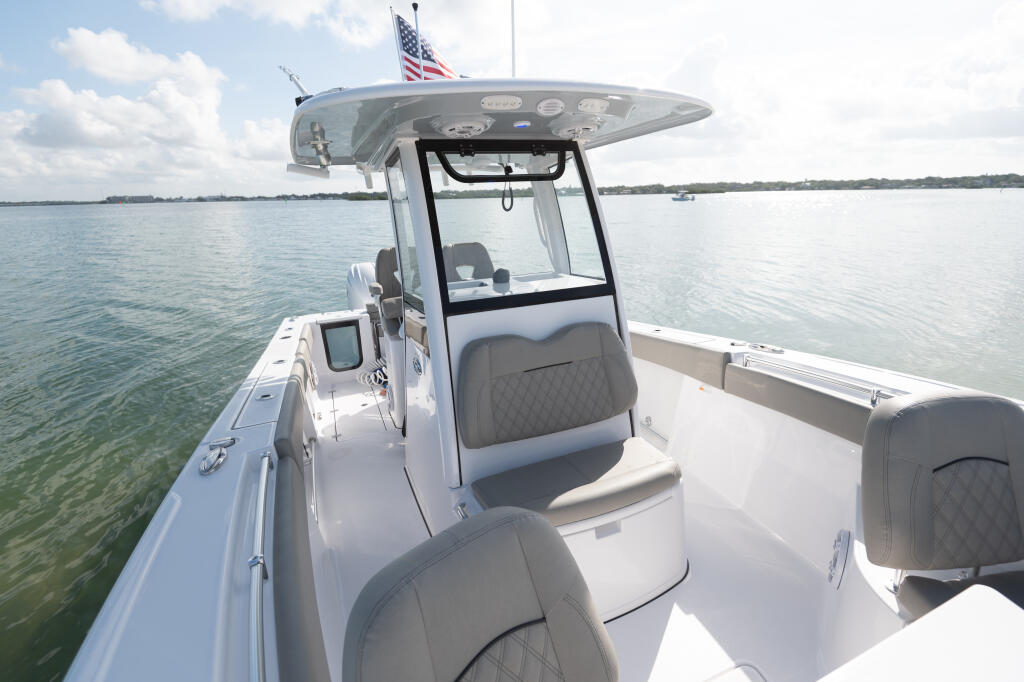 Center console boat with integrated tempered glass windshield and manual vent on calm coastal waters
