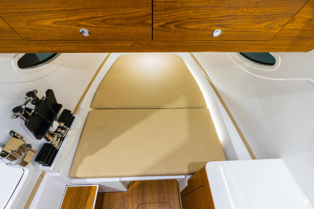 Overhead view of boat cabin interior with tan cushioned seating, wood trim, and porthole windows