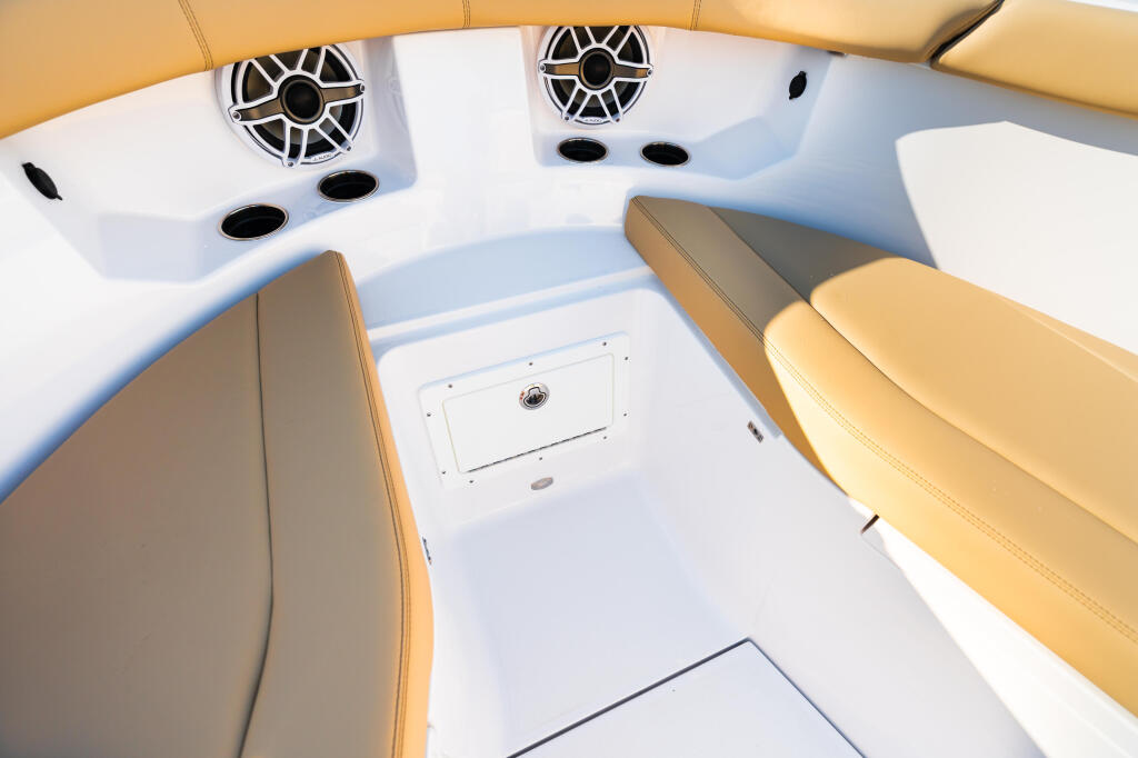 Boat cabin overhead view showing tan leather seating, white ceiling with speakers and lighting fixtures