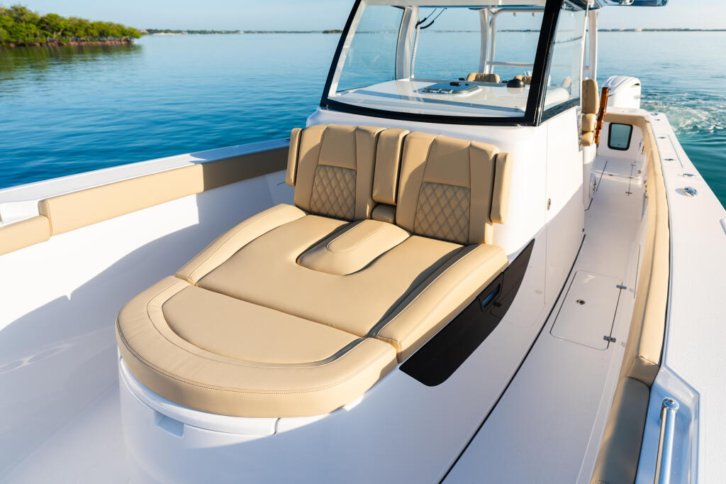 Tan leather seating in the open bow with windshield and calm blue water surrounding the boat