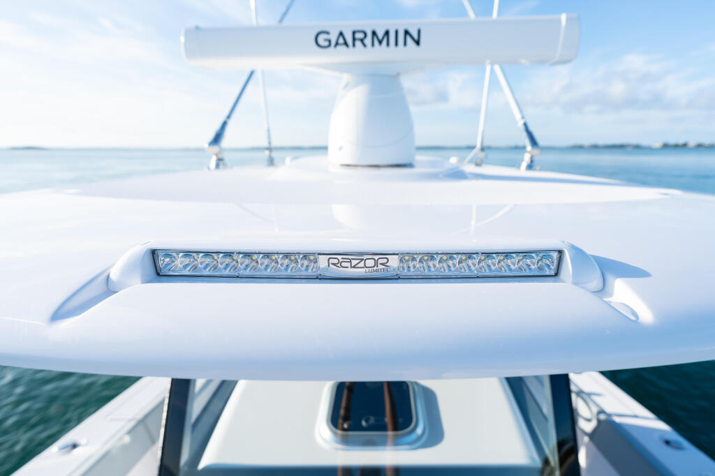 Garmin navigation system and Razor LED light bar mounted on boat hardtop with calm water and coastline in background