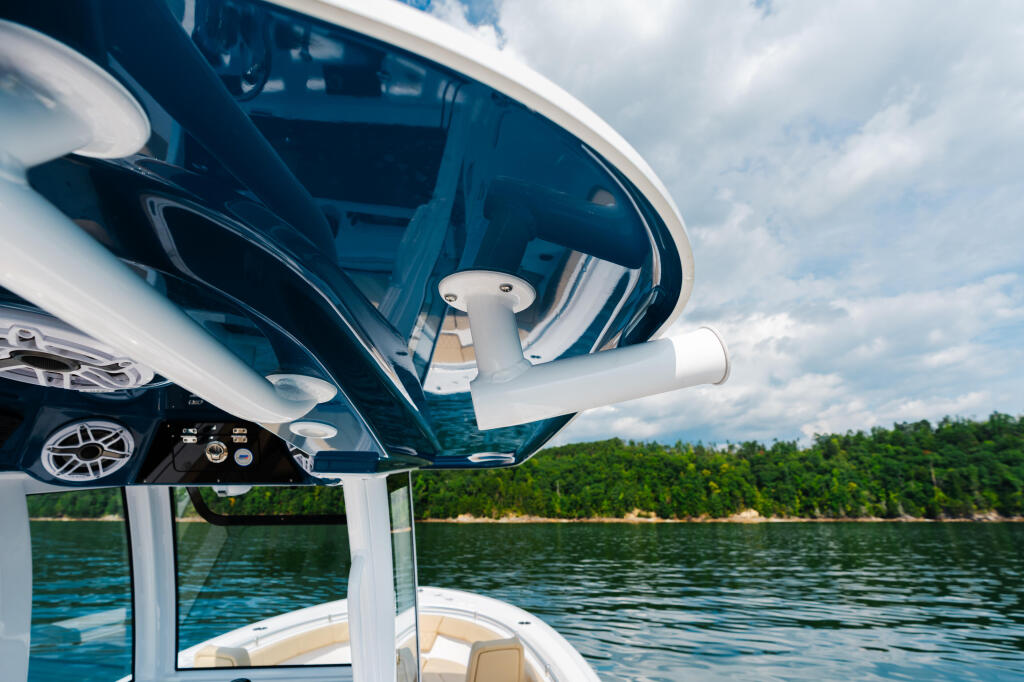 Hard-top canopy and windshield of a boat on a forested lake under partly cloudy skies