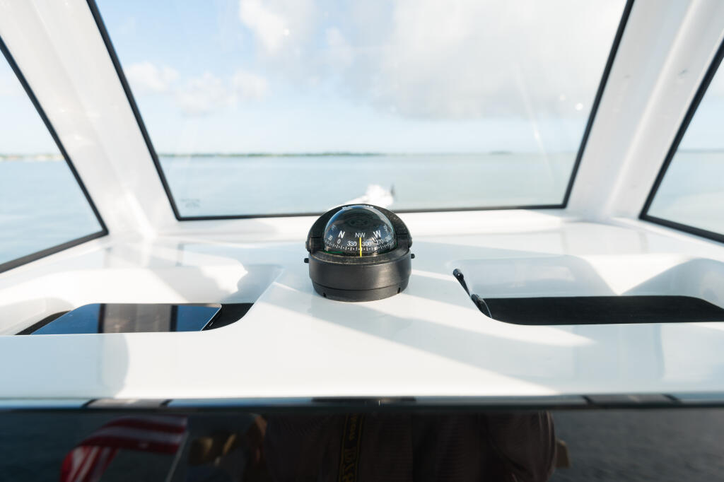 Compass mounted on boat console with windshield and calm water view beyond