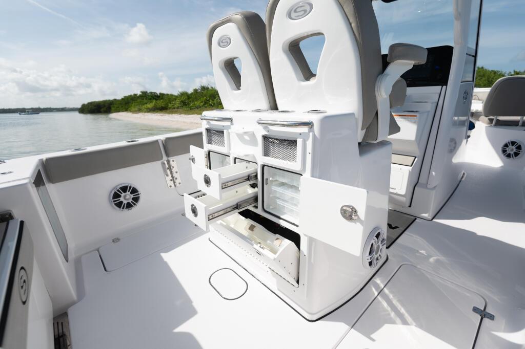 Center console with open tackle storage and coolers overlooking a sandy beach and calm waters