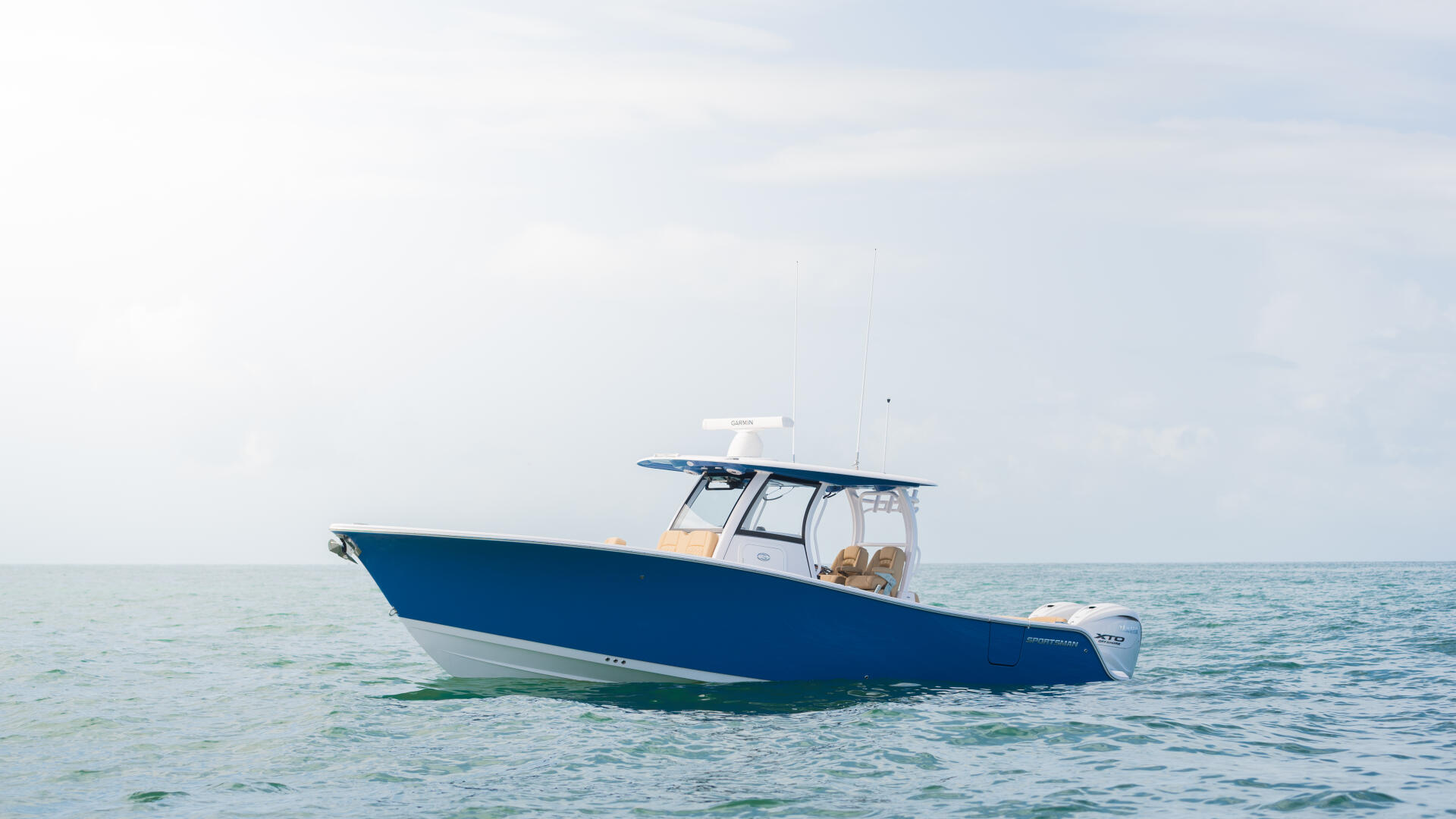 Blue and white center console fishing boat anchored in shallow turquoise water