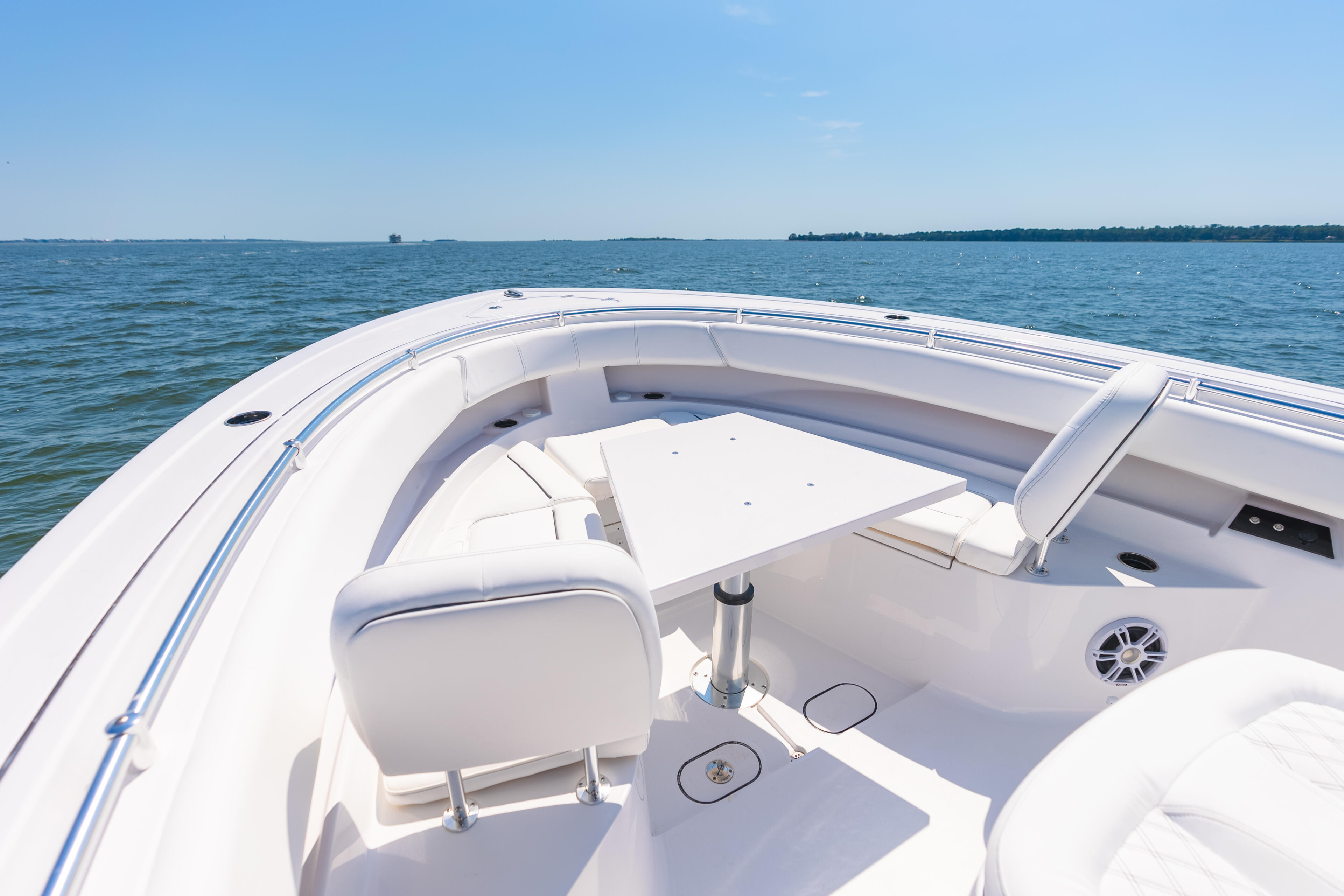 Spacious open bow seating area with white upholstered seats and modern helm on a boat underway in calm blue water