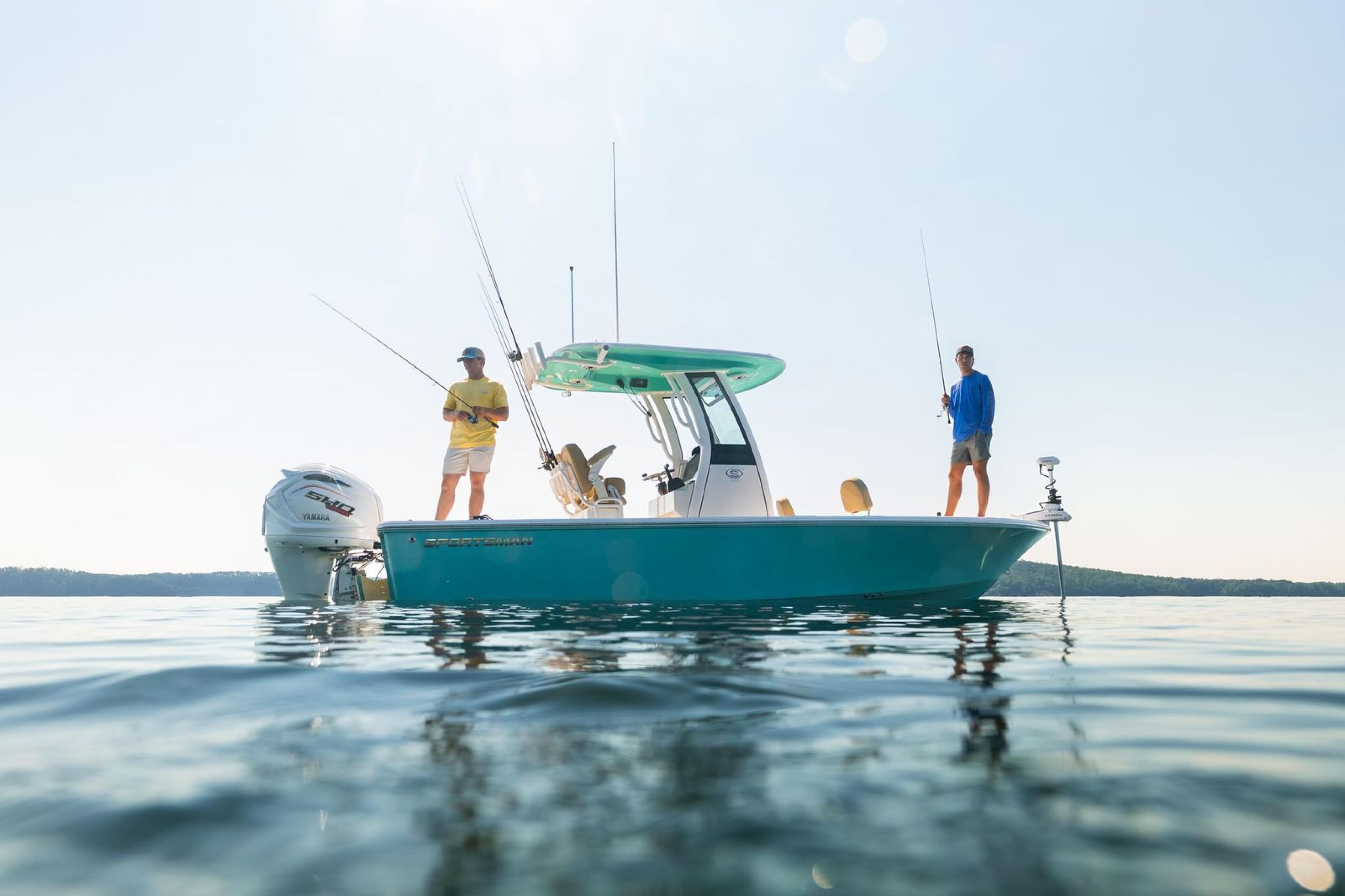 Turquoise fishing boat with four anglers and fishing rods anchored in shallow coastal waters