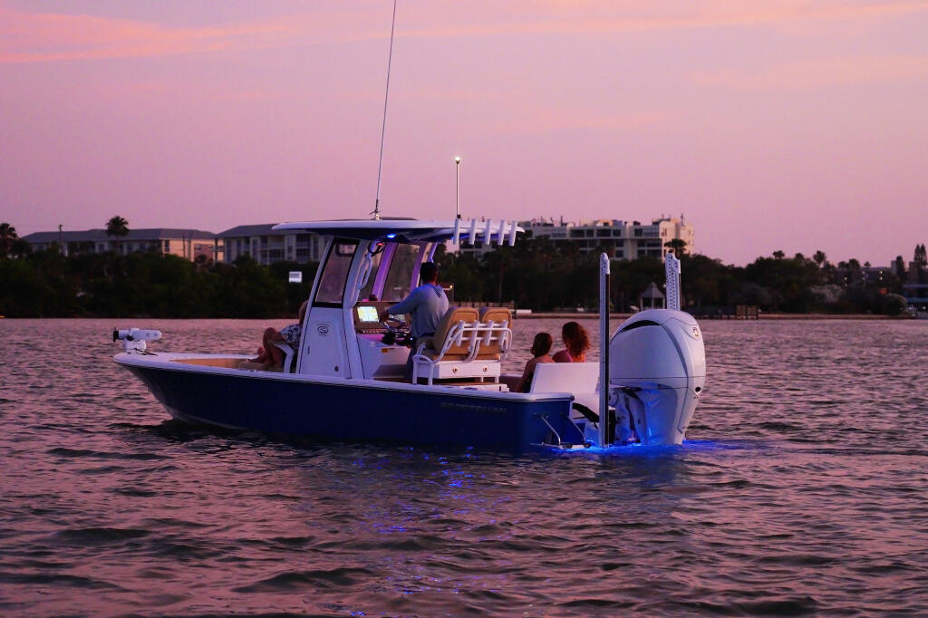 Boat anchored at sunset with blue underwater lighting illuminating the hull and water