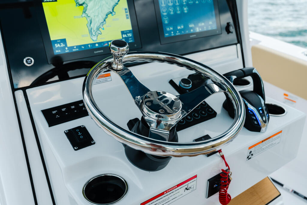 Chrome steering wheel and helm display with Garmin electronics showing navigation charts and water conditions