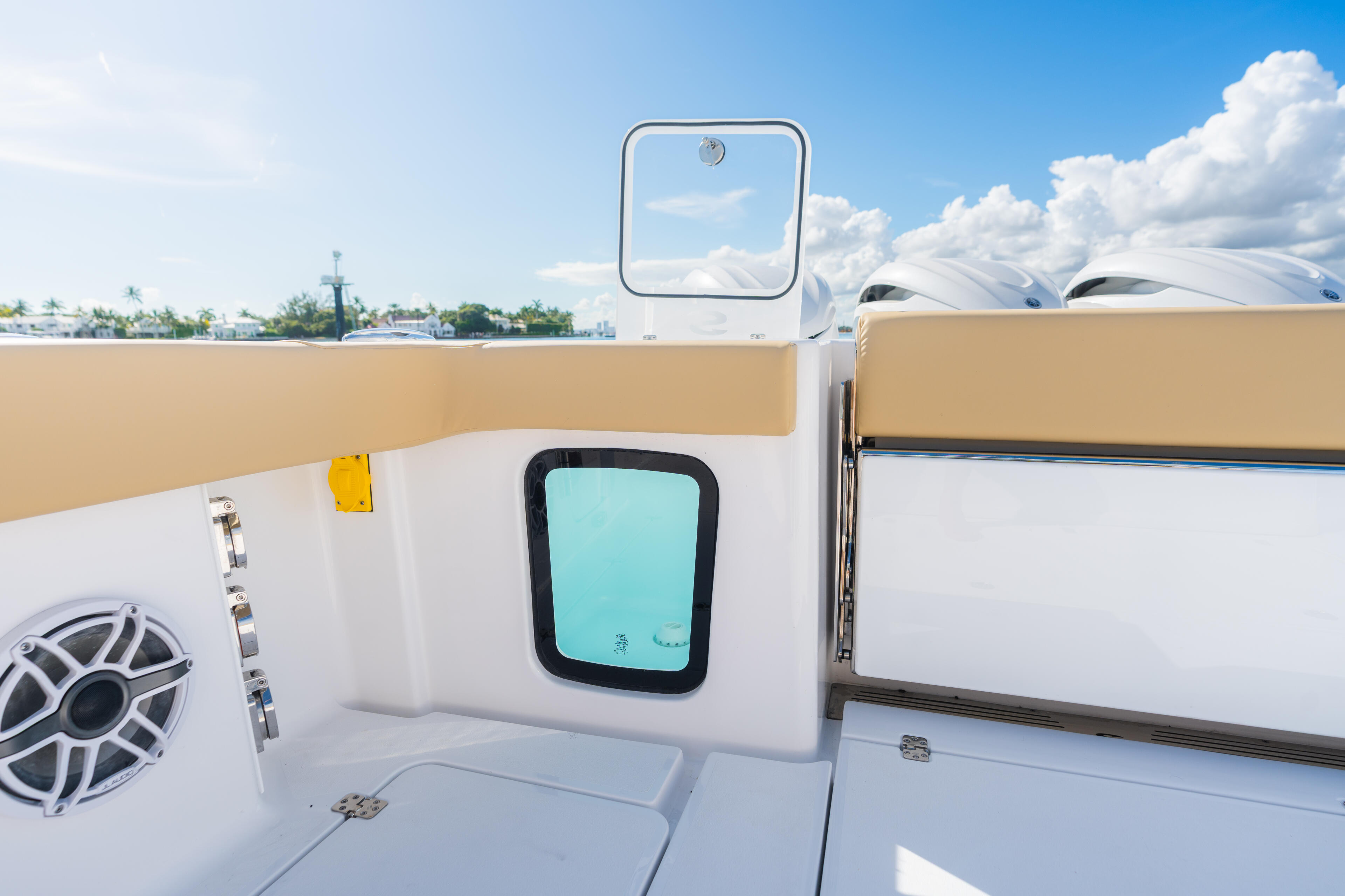 Boat cabin exterior with teal porthole window, audio speaker, and hardtop against marina backdrop