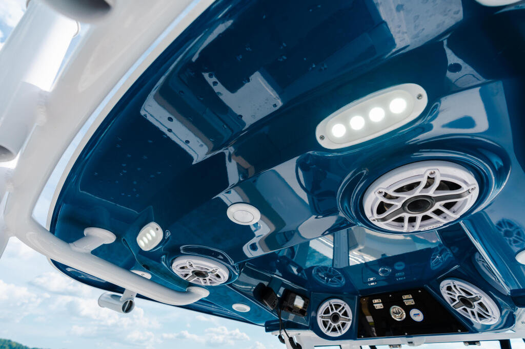 Cabin ceiling interior with LED lighting, speakers, and electronics control panel in a blue boat