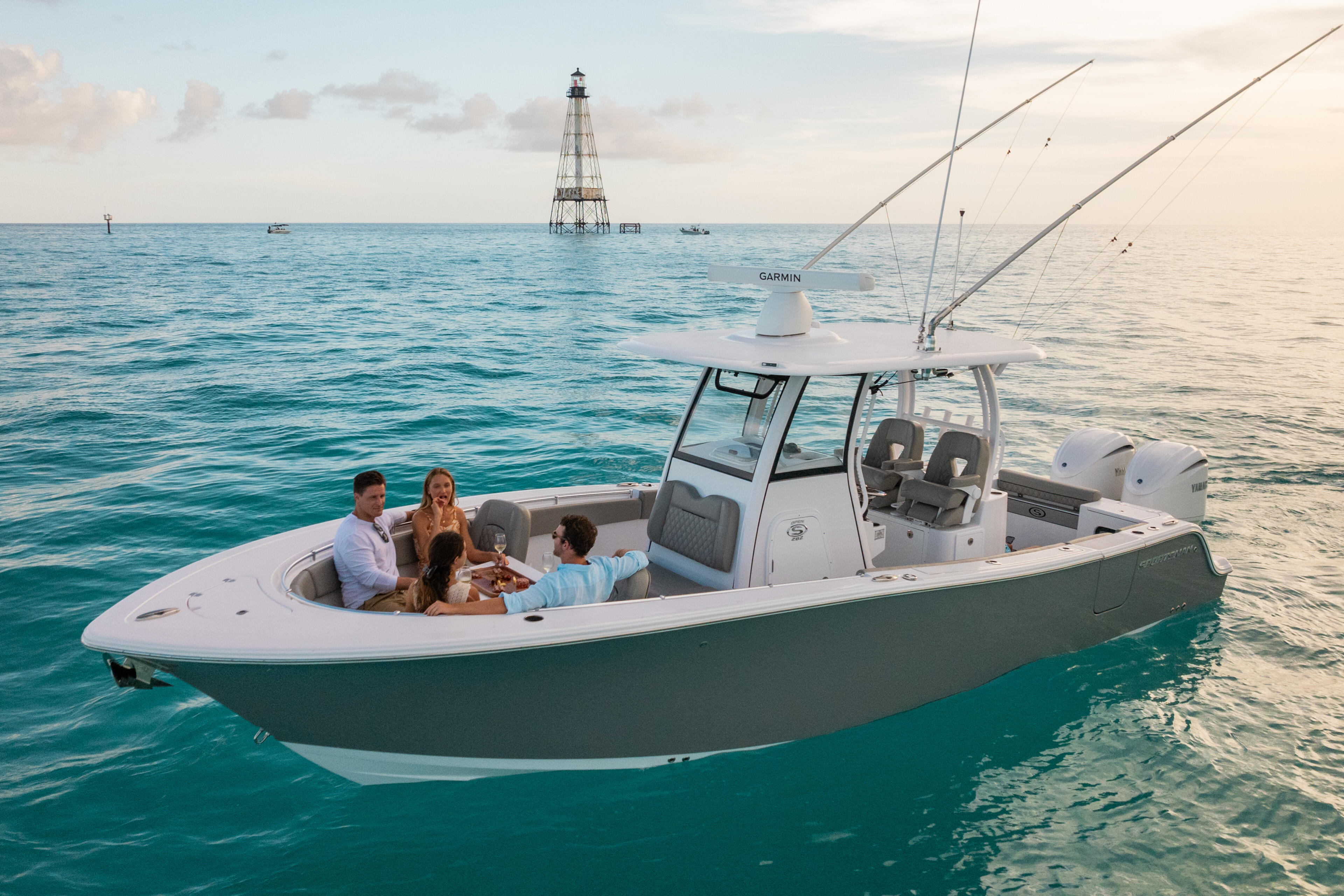 Fishing boat anchored offshore with four people enjoying drinks and conversation during golden hour