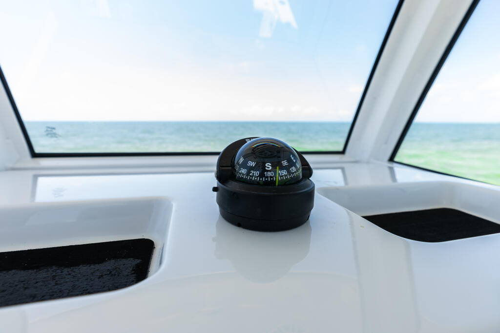 Compass mounted on the helm console with ocean and sky visible through the hard-top windshield