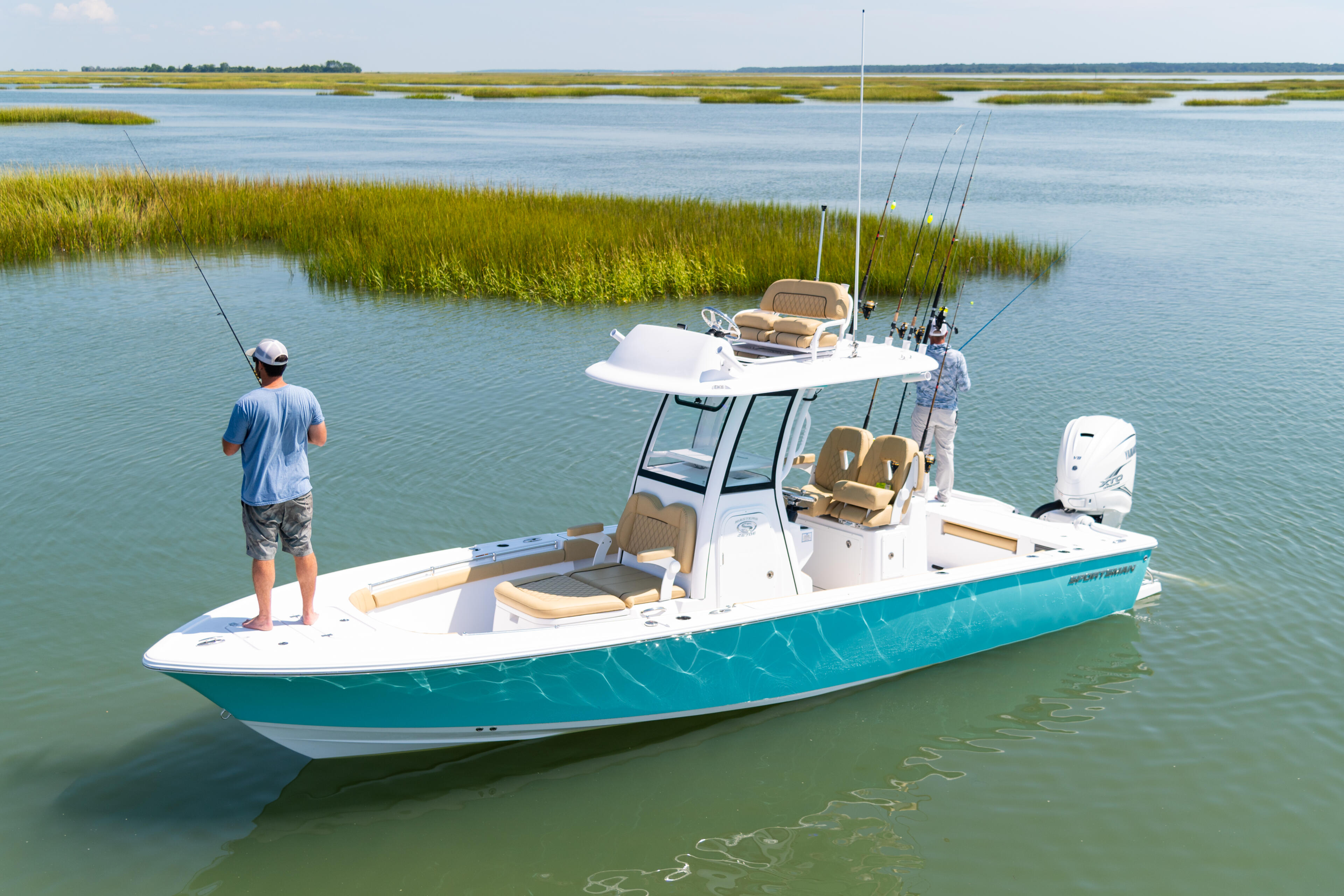 Fishing boat with two anglers anchored in shallow coastal waters near marsh grasses