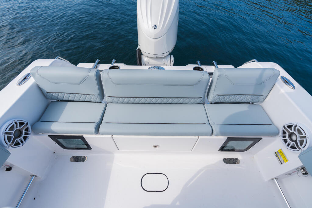 Overhead view of white center console boat's rear seating with gray cushioned bench seats and integrated speaker systems