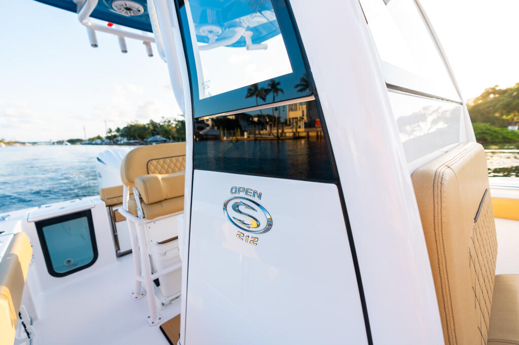 Center console boat interior with tan quilted seating and large windshield overlooking waterfront marina