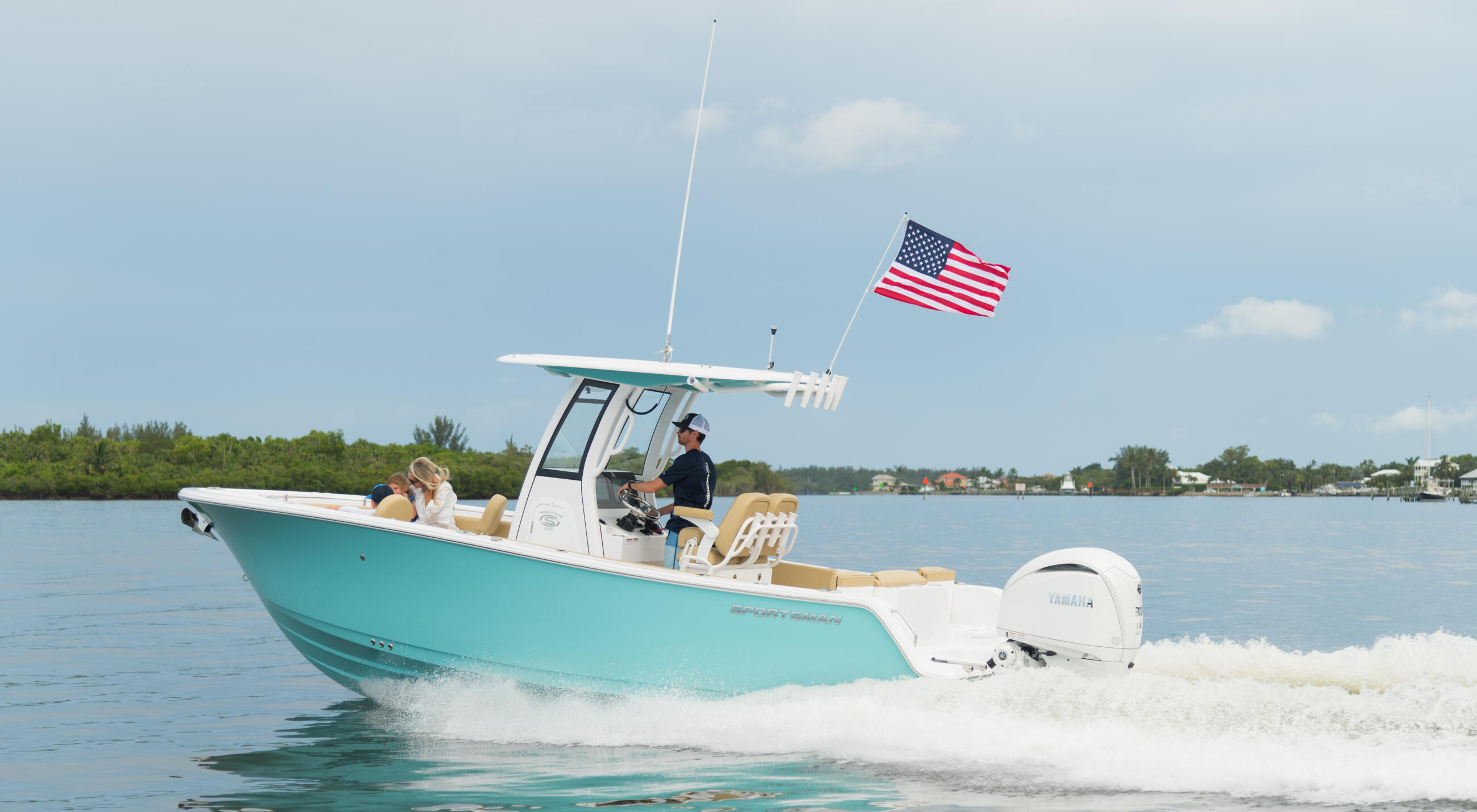 Turquoise and white center console boat running through shallow water near a sandbar with American flag flying