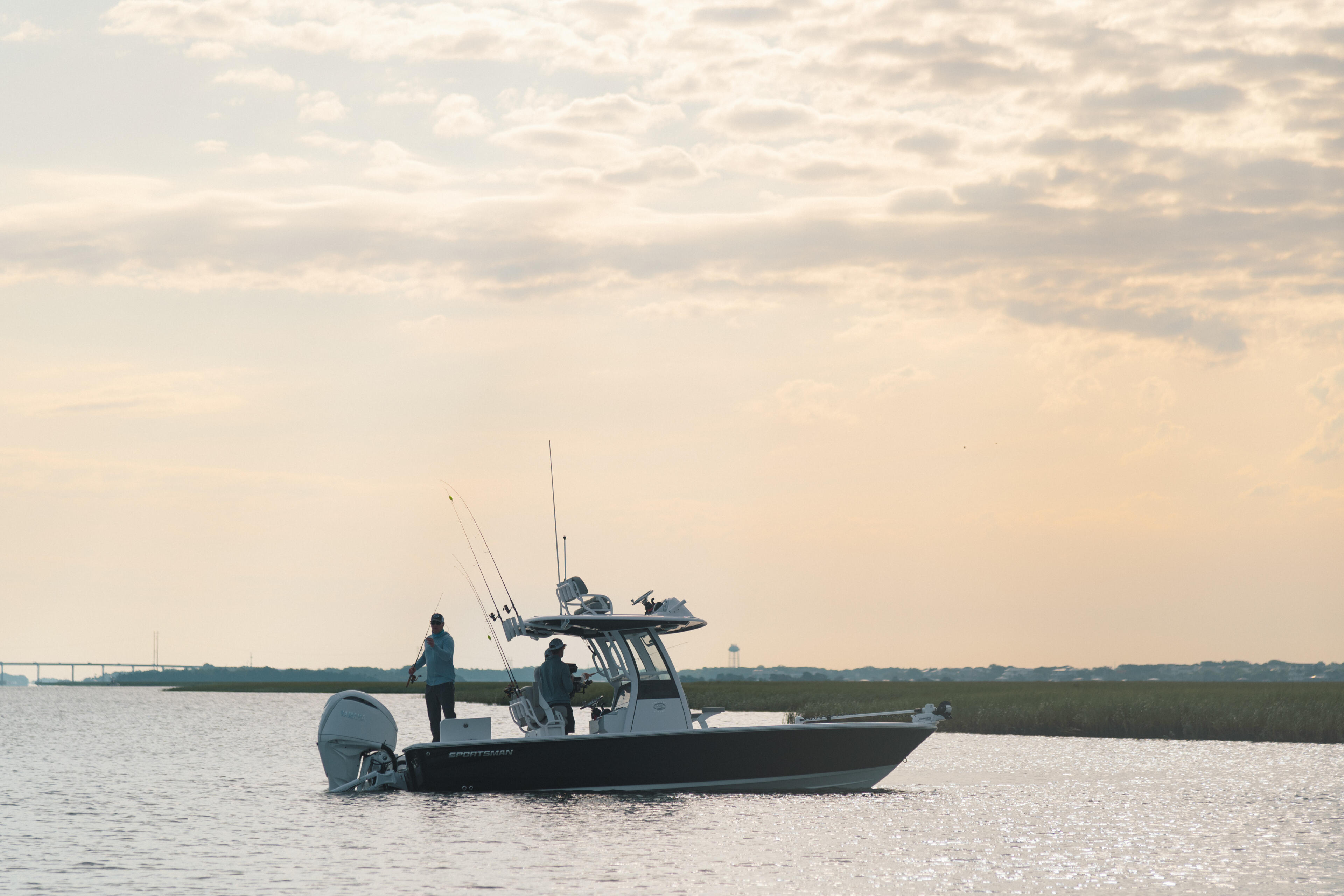 Fishing boat with two anglers anchored in shallow coastal waters at sunset