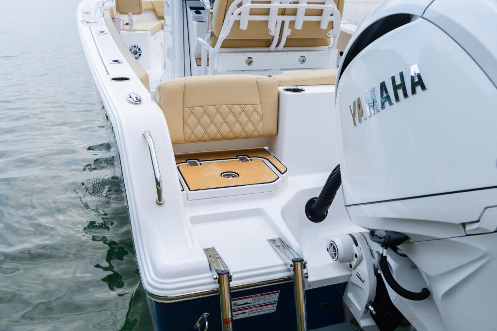 Stern view of white and tan center console boat with Yamaha outboard engine at water's edge