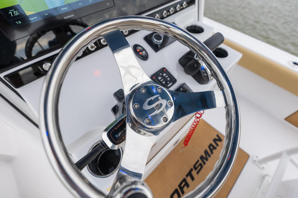 Polished stainless steel boat steering wheel with blue grip and Sea-Star hydraulic controls at the helm