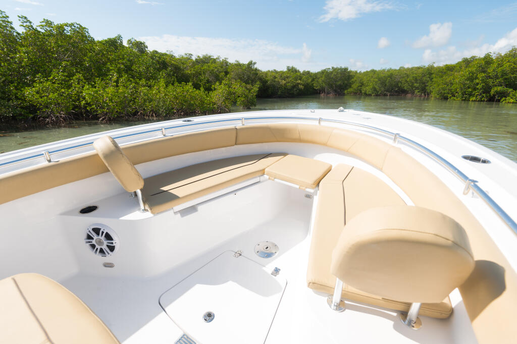 Spacious open-bow seating with cream cushions and white deck overlooking mangrove waterway
