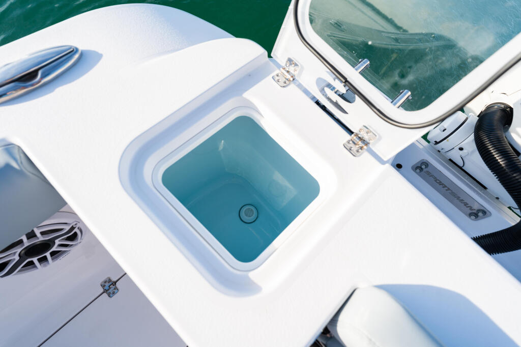 Open livewell with turquoise water visible, mounted on white fiberglass boat deck with windshield and hatches