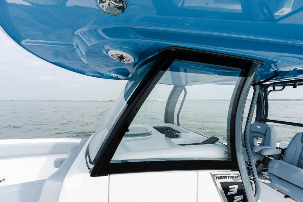 Blue hard-top windshield and helm area of a boat on calm offshore waters